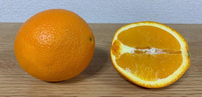 半分にカットされたオレンジとカットされていないオレンジの写真